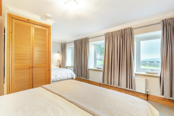 A hotel room with a bed, a wardrobe, a window with curtains, and a view of the outside. - 2 Bed in Cowling (oc-ds238) (Cowling)