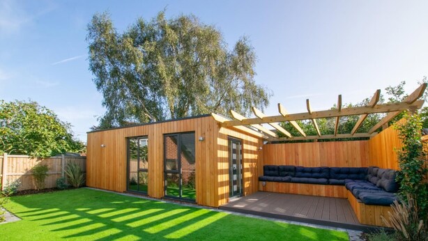 Eine moderne Außenpatio mit Holz-Pergola, einer integrierten Sitzgruppe und einem gepflegten Rasen.