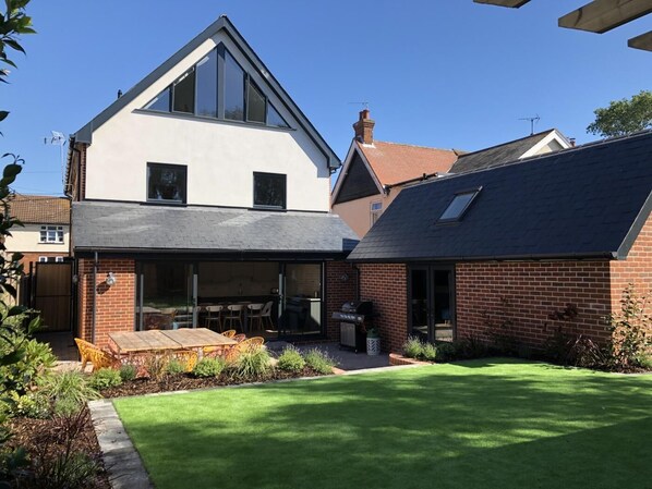 A modern two-story house with a large glass patio, a brick exterior, and a well-maintained lawn. - 5 Bed in Southwold (oc-nort) (Southwold)
