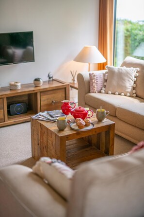 Ein Wohnzimmer mit Couch, Fernseher, Lampe und einem Holztisch.