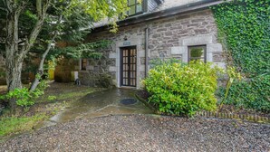 A stone building with a wooden door, surrounded by greenery and a gravel path. - 2 Bed in Methven (oc-c32362) (Methven)