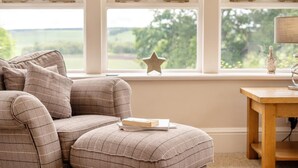 A cozy room with a checkered sofa, a wooden side table, and a star decoration on the windowsill. - 2 Bed in Methven (oc-c32362) (Methven)