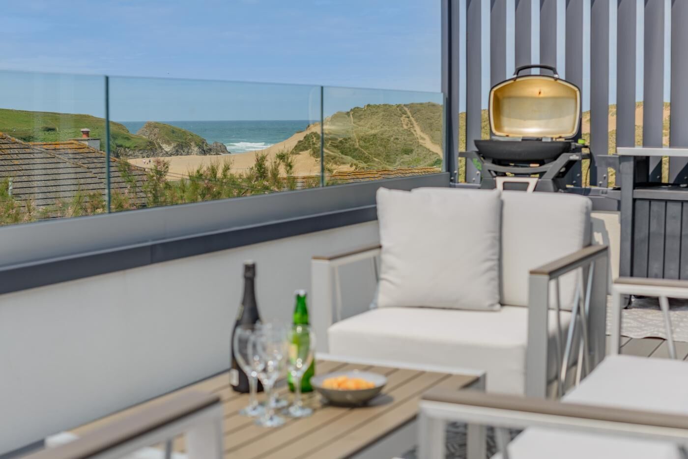Un balcone con vista sulla spiaggia e sulle dune, dotato di barbecue e mobili da esterno.