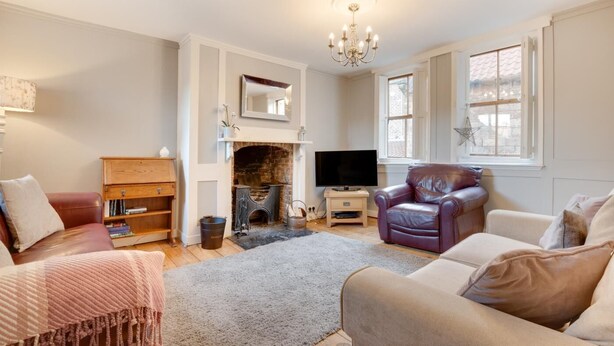 A living room with a fireplace, a television, leather chairs, and a bookshelf. - 2 Bed in Whitby (oc-w003) (Whitby)