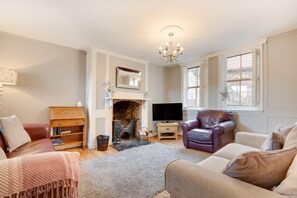 A living room with a fireplace, a television, leather chairs, and a bookshelf. - 2 Bed in Whitby (oc-w003) (Whitby)