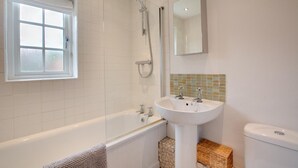 Ein Badezimmer mit Badewanne, Waschbecken, Toilette, Fenster und Spiegel.