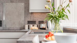 A modern kitchen with a built-in oven, a toaster, and a coffee maker. - 1 Bed in Newquay (oc-o32401) (Holywell)