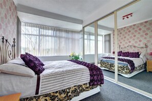 A bedroom with a large mirror, a bed with striped bedding, and a window with blinds. - 6 Bed in Scarborough (oc-s871) (Scarborough)
