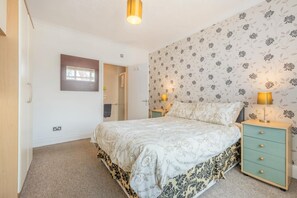 A bedroom with a bed, two bedside tables, a nightstand, a wall-mounted lamp, and a door leading to another room. - 6 Bed in Scarborough (oc-s871) (Scarborough)