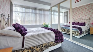 A bedroom with a large mirror, a bed with striped bedding, and a window with blinds. - 6 Bed in Scarborough (oc-s871) (Scarborough)