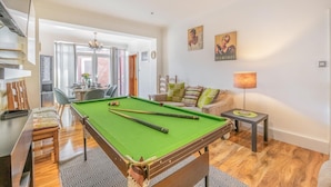 A pool table in a well-lit room with a dining area, a sofa, and artwork on the wall. - 6 Bed in Scarborough (oc-s871) (Scarborough)