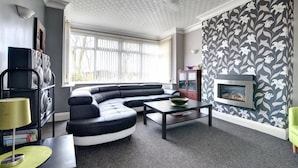 A modern living room with a sectional sofa, a fireplace, and a patterned wall. - 6 Bed in Scarborough (oc-s871) (Scarborough)