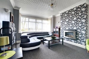 A modern living room with a sectional sofa, a fireplace, and a patterned wall. - 6 Bed in Scarborough (oc-s871) (Scarborough)