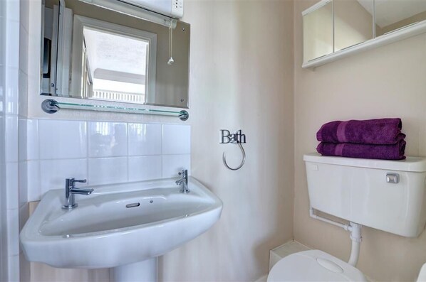 A bathroom with a white sink, a toilet, and a glass shelf above the sink. - 6 Bed in Scarborough (oc-s871) (Scarborough)