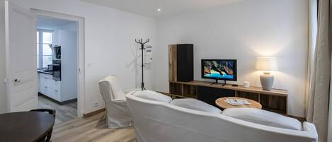 A modern living room with a sofa, a television, a lamp, and a wooden cabinet.