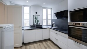 Eine moderne Küche mit weißen Schränken, einer schwarzen Arbeitsplatte, einem eingebauten Backofen und einem Fenster mit Blick.
