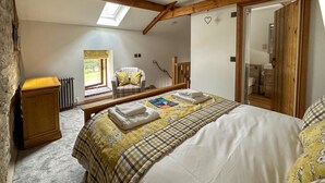 Ein Schlafzimmer mit Bett, Stuhl, Heizkörper, Fenster und Spiegel.