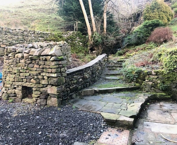 A stone wall with a stone staircase leading up to a higher level. - 3 Bed in Sedbergh (oc-ds169) (Garsdale)