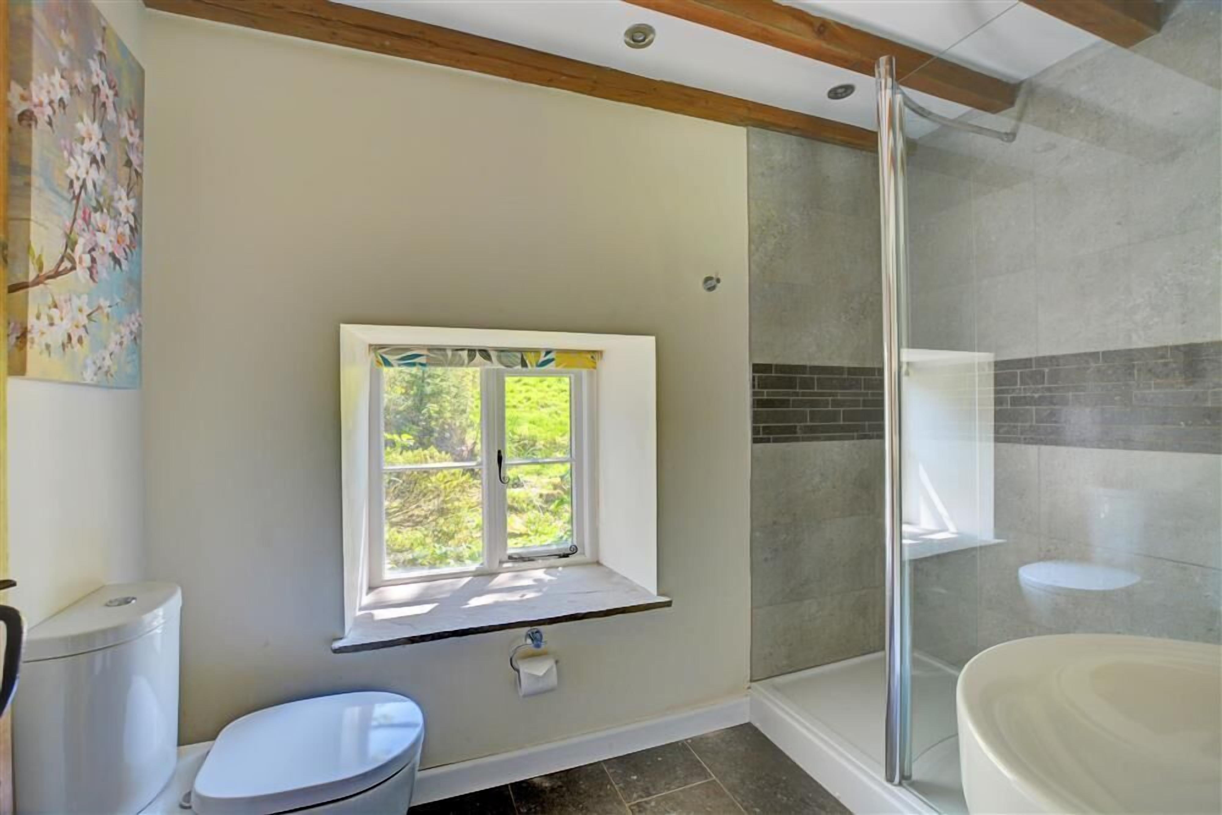 Une salle de bain avec des toilettes, une fenêtre, une douche et un lavabo.