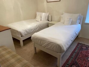 A room with two single beds, a small bedside table, a bench, and a patterned rug. - 3 Bed in Sedbergh (oc-ds169) (Garsdale)