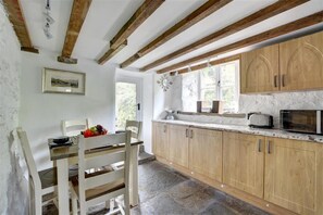 A kitchen with wooden cabinets, a stone countertop, and a window with natural light. - 3 Bed in Sedbergh (oc-ds169) (Garsdale)