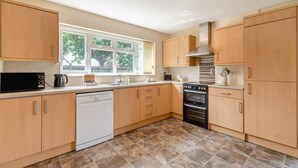 A modern kitchen with wooden cabinets, a dishwasher, a stove, and a window providing natural light. - 1 Bed in Flore (oc-b32437) (Flore)