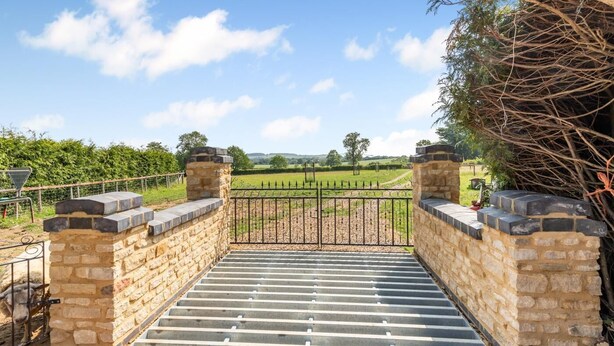 A stone staircase leading to a metal gate with a view of a rural landscape. - 1 Bed in Flore (oc-b32437) (Flore)