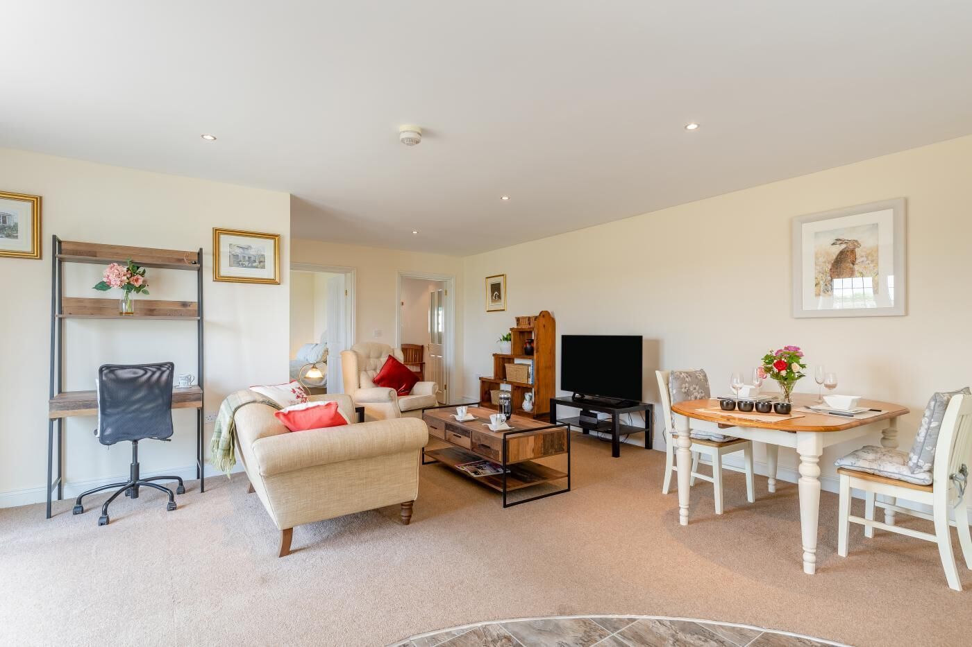 A living room with a sofa, armchairs, a coffee table, a TV, and a dining table with chairs.