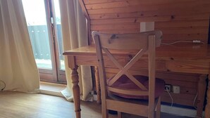 Ein Stuhl aus Holz mit Kreuzrückenlehne, platziert neben einem Tisch mit Holzbeschichtung.
