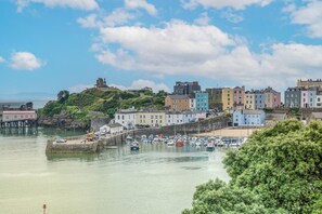 A coastal town with historic buildings, a harbor with boats, and a prominent lighthouse. - 3 Bed in Tenby (oc-p32426) (Tenby)