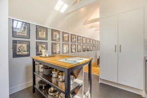 A kitchen with a wooden table, metal shelves, and a white cabinet.
