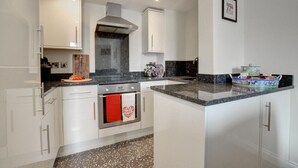 A modern kitchen with white cabinets, a stainless steel range hood, a built-in oven, and a granite countertop. - 2 Bed in Whitby (oc-w979) (Whitby)