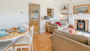 Una sala de estar acogedora con chimenea, un comedor con mesa de madera y una cocina al fondo.