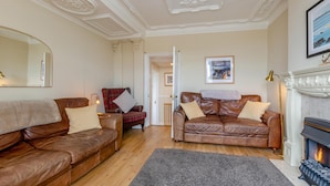 A room with two leather sofas, a fireplace, and a mirror on the wall. - 3 Bed in Whitby (oc-w957) (Whitby)