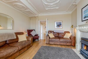 Ein Zimmer mit zwei Ledersofas, einem Kamin und einem Spiegel an der Wand.