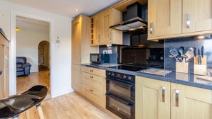 A modern kitchen with wooden cabinets, a black countertop, and stainless steel appliances. - 3 Bed in Whitby (oc-w957) (Whitby)