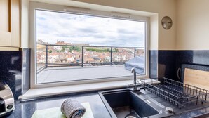 A kitchen with a large window overlooking a cityscape, a sink, and a stove. - 3 Bed in Whitby (oc-w957) (Whitby)