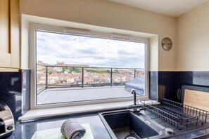 Eine Küche mit großem Fenster und Blick auf die Stadt, ein Spülbecken und ein Herd.