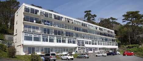 Un immeuble à plusieurs étages avec un parking situé à l’avant.