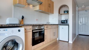 Een moderne keuken met houten kastjes, een inbouwoven, een vaatwasser en een wasmachine.