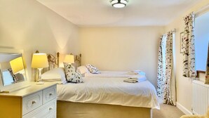 A bedroom with two beds, a bedside table with lamps, a dresser, and a chair. - 3 Bed in Gunnerside (oc-ds067) (Gunnerside)