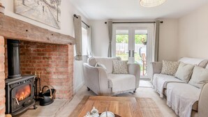 A cozy living room with a brick fireplace, two sofas, a coffee table, and a hanging light fixture. - 3 Bed in Alfrick (oc-s32386) (Alfrick)