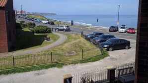 A coastal road with parked cars, a pedestrian path, and a view of the sea. - 2 Bed in Whitby (oc-w507) (Whitby)