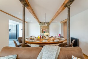 A dining area with a round table set for six, surrounded by wooden beams and stone walls. - 5 Bed in Wigglesworth (oc-w32112) (Wigglesworth)