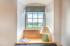 Ein Zimmer mit Fenster, Lampe, Zeitschrift und Klavier.