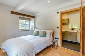 A bedroom with a bed, a window with a view, a bedside table, and a door leading to a bathroom. - 5 Bed in Wigglesworth (oc-w32112) (Wigglesworth)