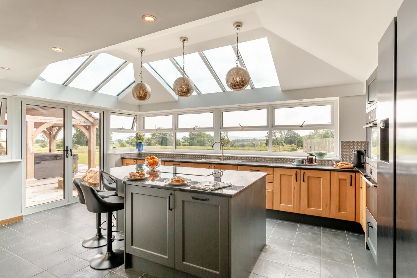 A modern kitchen with a large island, skylights, and a view of the outdoors.