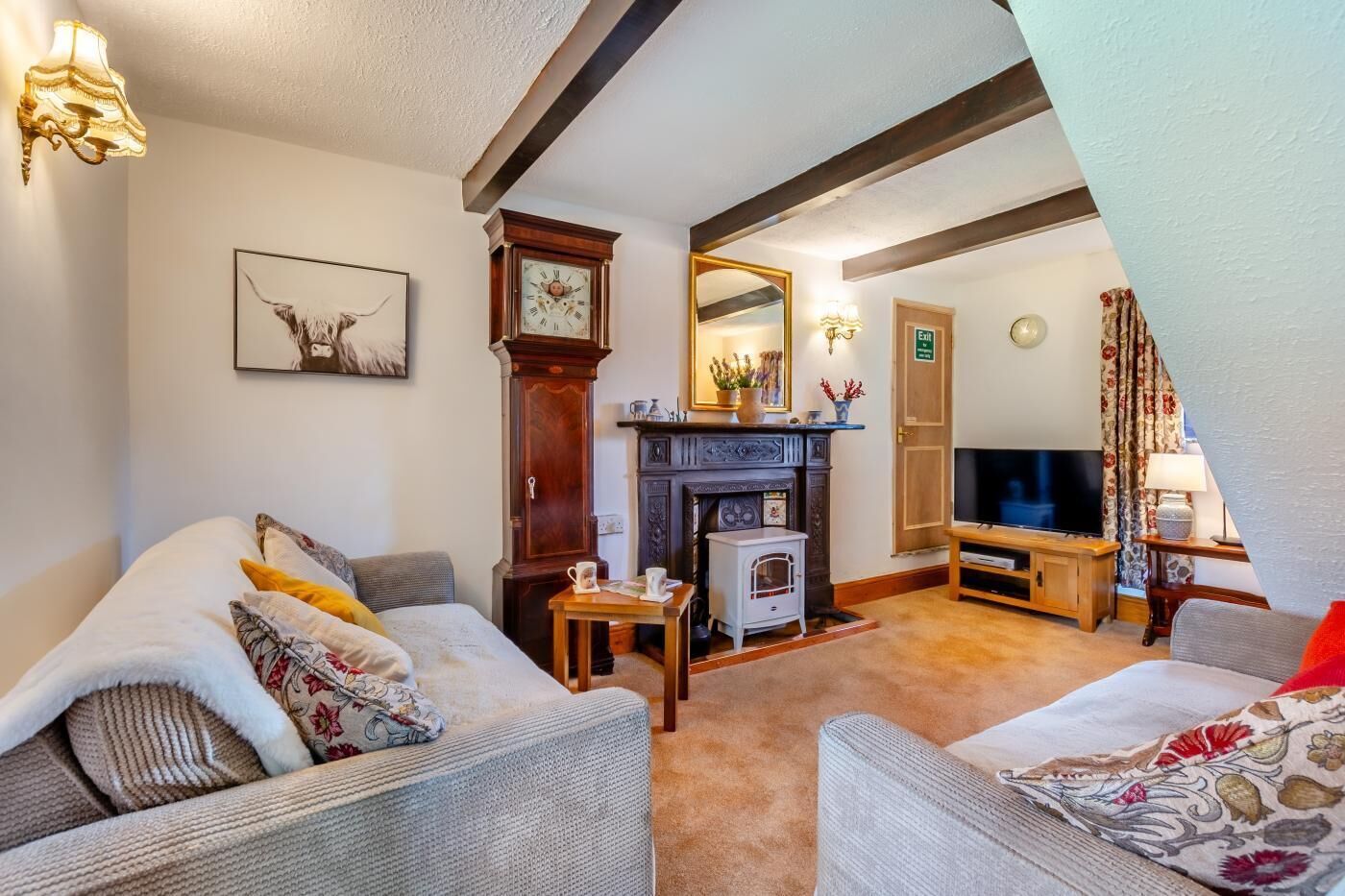 A cozy living room with a fireplace, a large clock, and a television.