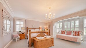 A bedroom with a large bed, a wooden dresser, a chair, a bench, and a chandelier. - 4 Bed in Scarborough (oc-sa870) (Scalby)