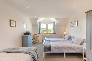 Une chambre avec deux lits, une commode, une chaise et une fenêtre donnant sur un beau paysage.